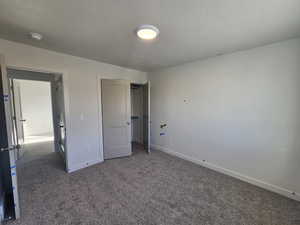 Unfurnished bedroom featuring carpet flooring, a textured ceiling, and a closet