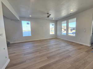 Empty room with light wood-style floors, stairs, a ceiling fan, recessed lighting, and a textured ceiling