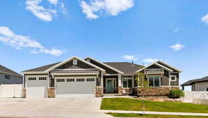 Craftsman house with board and batten siding, stone siding, an attached garage, driveway, and a standing seam roof
