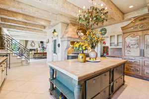 Kitchen featuring open shelves, decorative backsplash, light tile patterned floors, beam ceiling, and a center island