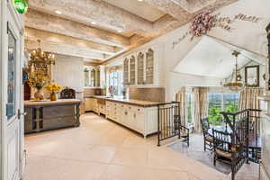 Kitchen with a chandelier, glass insert cabinets, beam ceiling, backsplash, and light tile patterned floors