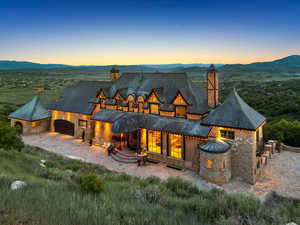Back of property featuring a chimney, a mountain view, an attached garage, and stone siding