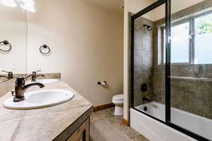 Full bathroom featuring double vanity, combined bath / shower with glass door, and tile patterned flooring