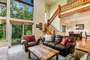 Living room with stairway, a towering ceiling, plenty of natural light, and a chandelier