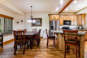 Kitchen with black microwave, stove, stainless steel refrigerator with ice dispenser, wood finished floors, and a center island