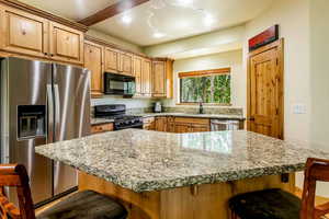 Kitchen featuring stainless steel appliances, a kitchen breakfast bar, light stone counters, a kitchen island, and recessed lighting