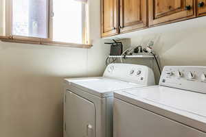 Laundry area with separate washer and dryer, cabinet space, and plenty of natural light