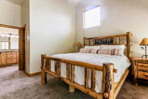 Bedroom featuring light colored carpet, high vaulted ceiling, and connected bathroom