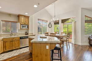 Kitchen with stainless steel appliances, a kitchen island, a kitchen bar, lofted ceiling, and a chandelier