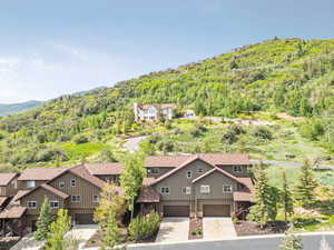 Aerial view of property and surrounding area with a forest and mountains