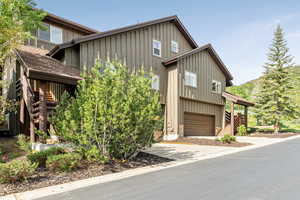 View of front facade featuring board and batten siding, stairway, an attached garage, and concrete driveway