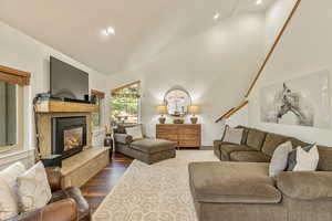 Living area featuring lofted ceiling, dark wood-type flooring, recessed lighting, and a premium fireplace