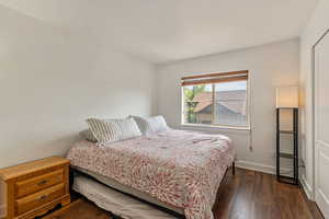Bedroom with dark wood-style flooring and baseboards