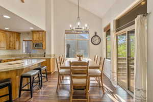 Dining room with dark wood-type flooring, a chandelier, recessed lighting, and high vaulted ceiling