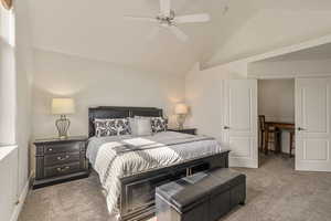 Carpeted bedroom featuring ceiling fan and high vaulted ceiling