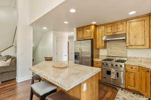Kitchen featuring appliances with stainless steel finishes, under cabinet range hood, dark wood-style flooring, light countertops, and recessed lighting