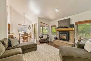 Living area with wood finished floors, a fireplace, a chandelier, and high vaulted ceiling