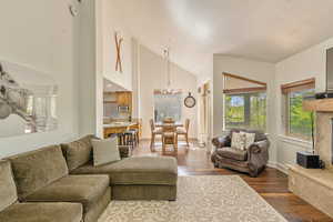 Living area featuring dark wood-style floors, a chandelier, and high vaulted ceiling