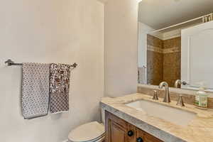 Bathroom with a textured wall, vanity, and a shower