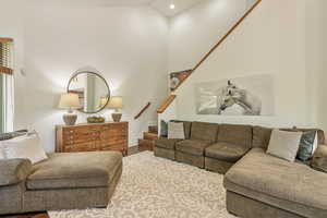 Living room featuring stairs, lofted ceiling, wood finished floors, and recessed lighting