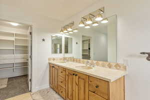 Bathroom with double vanity, backsplash, and a spacious closet
