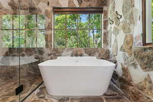 Full bath featuring a soaking tub and a marble finish shower