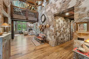 Living area with wood-type flooring, beamed ceiling, a lit fireplace, and a chandelier