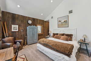 Bedroom with wood walls, carpet, high vaulted ceiling, and recessed lighting