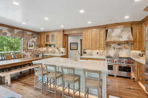 Kitchen featuring custom range hood, range with two ovens, tasteful backsplash, light wood-type flooring, and recessed lighting