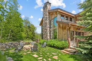 Rear view of house with a fire pit, a chimney, a lawn, and board and batten siding