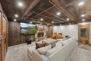 Living area featuring carpet floors, a stone fireplace, and wooden walls