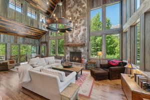 Living room with high vaulted ceiling, hardwood / wood-style flooring, a fireplace, wooden ceiling, and wood walls