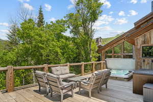 Deck featuring a covered hot tub and outdoor lounge area