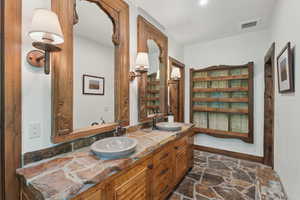 Full bath with double vanity and stone finish flooring