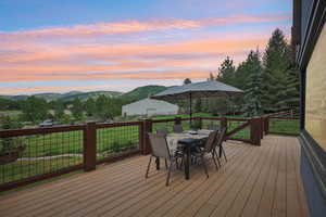 Deck at dusk featuring outdoor dining area and a mountain view