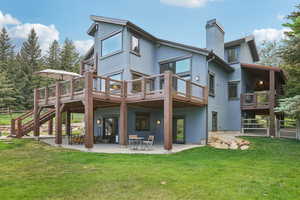 Rear view of property featuring a chimney, stucco siding, and a patio area