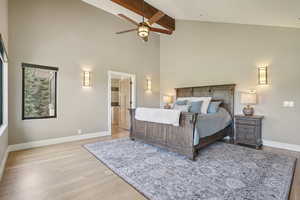 Bedroom featuring high vaulted ceiling, light wood-type flooring, beam ceiling, and ensuite bath