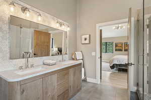 Bathroom featuring ensuite bathroom, double vanity, a stall shower, tile patterned flooring, and a chandelier