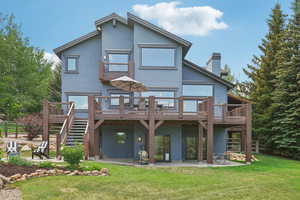 Rear view of house featuring a patio area, a wooden deck, stucco siding, and stairway