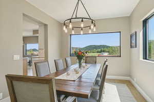 Dining room with light wood finished floors, healthy amount of natural light, and a chandelier