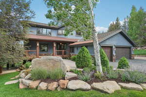 View of front of property featuring a porch, concrete driveway, stone siding, and a garage
