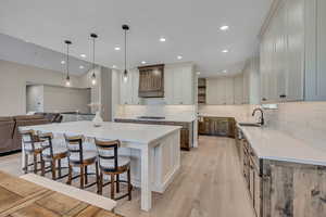 Kitchen with stainless steel gas stovetop, light wood-style flooring, decorative backsplash, a spacious island, and open floor plan