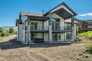 Rear view of property with a balcony, a hot tub, and a patio area