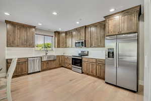 Kitchen featuring stainless steel appliances, light wood-style floors, backsplash, recessed lighting, and light countertops