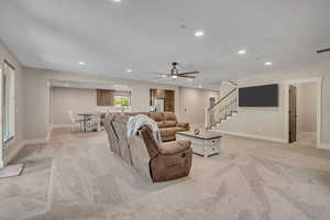 Living area featuring light colored carpet, a ceiling fan, stairway, recessed lighting, and a textured ceiling