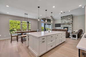 Kitchen featuring healthy amount of natural light, light wood-type flooring, white cabinets, recessed lighting, and vaulted ceiling