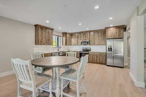Kitchen featuring appliances with stainless steel finishes, tasteful backsplash, light wood finished floors, recessed lighting, and light countertops