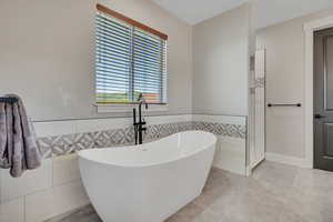 Full bath with a soaking tub, tile walls, and tile patterned floors