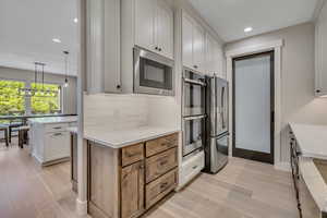 Kitchen with stainless steel appliances, light wood-type flooring, tasteful backsplash, light countertops, and recessed lighting