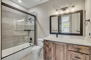 Full bath featuring combined bath / shower with glass door, vanity, ensuite bath, and tile patterned floors